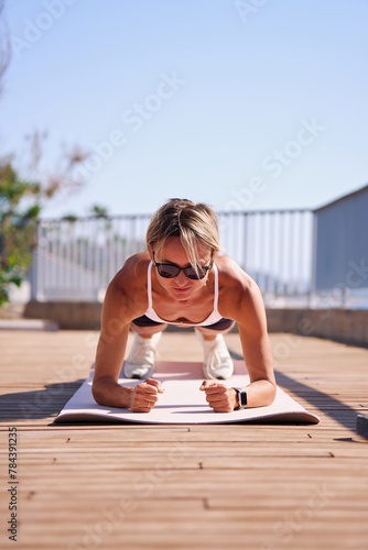 young caucasian woman in plank position, exercising outdoors. stretch whole body, lead healthy lifestyle. 