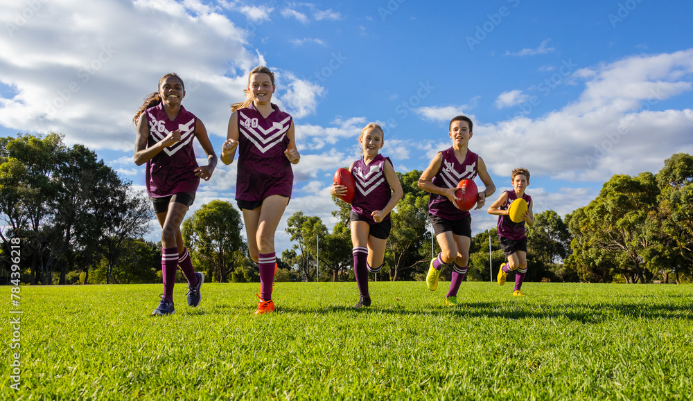 © Austockphoto - schoolchildren running towards camera in football uniforms on green grass