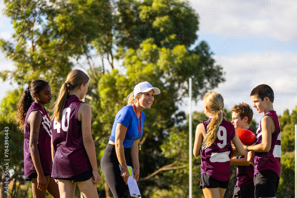 enthusiastic female coach encouraging her young football team enthusiastic female coach encouraging her young football team