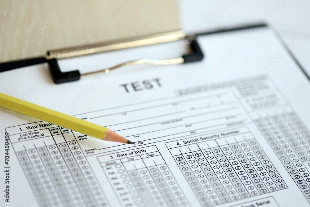 Blank educational test for students lies on table in classroom with pencil close up Blank educational test for students lies on table in classroom with pencil close up
