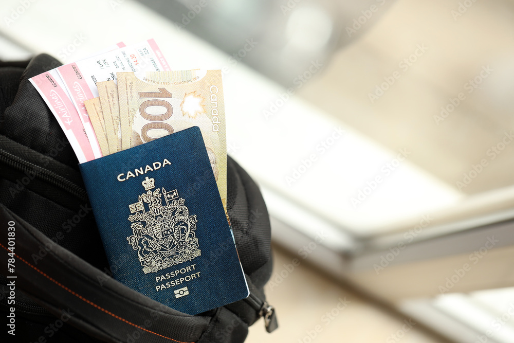 Fototapeta premium Canadian passport and dollar money bills with airline tickets on backpack close up