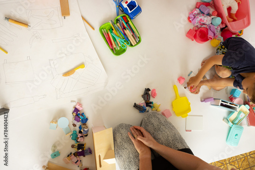 top down view of occupational therapist sitting on floor with child playing with toys photo