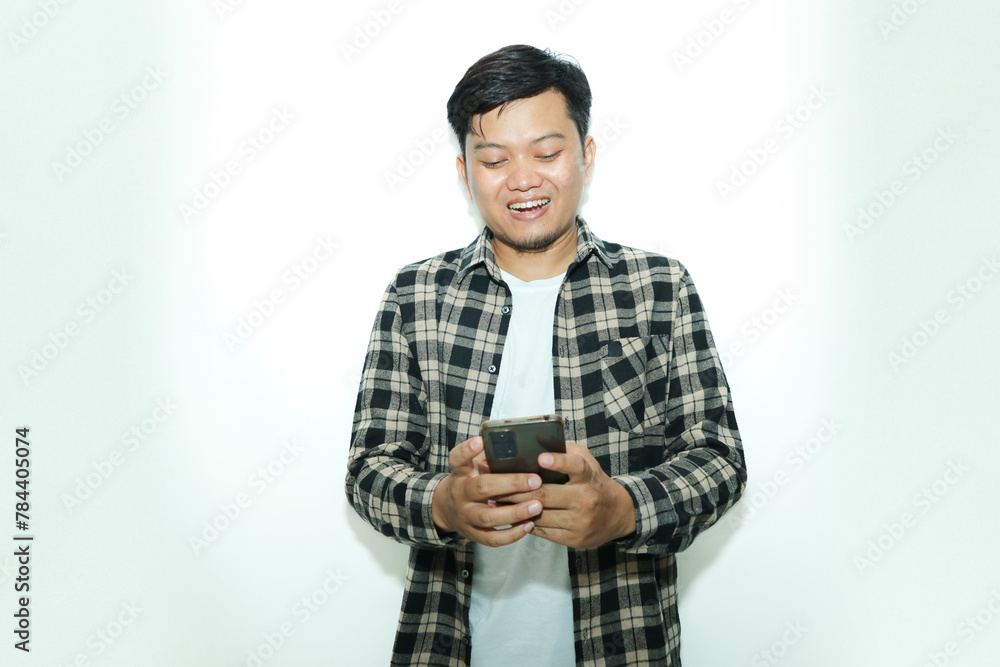 Young Asian man smiles while looking his mobile phone Young Asian man smiles while looking his mobile phone