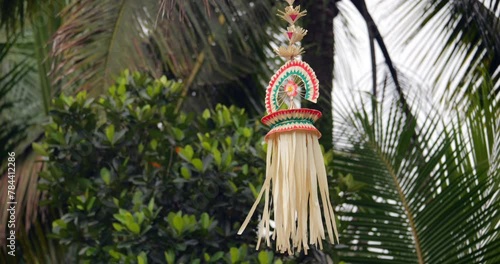 Street decoration at Balinese village street, close view of hanging Sampian penjor against blurred green plants on background. Traditional ornate craft from natural materials, street adornment at Bali photo