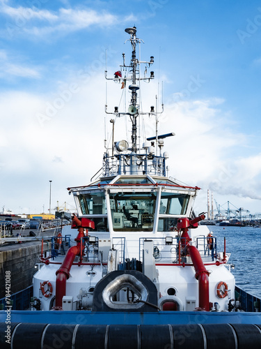 A front view of tugboat with white superstructure and red fire-fighting canons.