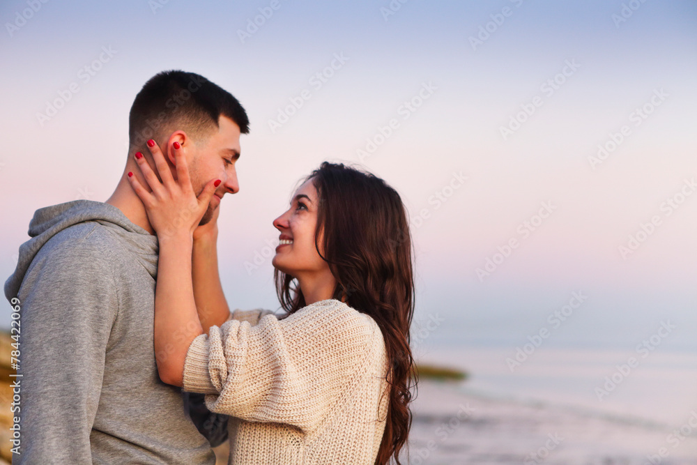 Young couple at rocky seacoast in sunset Young couple at rocky seacoast in sunset