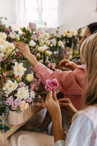 Floral workshop scene with participants arranging pink tulips and pastel flowers.