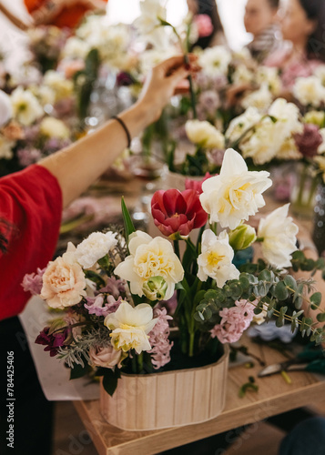 Vibrant flower arrangement session in progress  with a focus on a bright red tulip among pastel blooms.