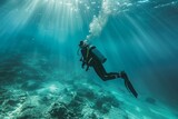 A solitary scuba diver is exploring the underwater seascape, immersed in the light-filled marine environment