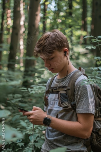 A young man standing in the woods with a cell phone. Suitable for technology or nature concepts