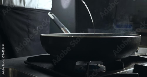 Chef using Olive Oil in frying pan. Cook preparing fried food on Kitchen Background. Close up shot of food preparetion. photo
