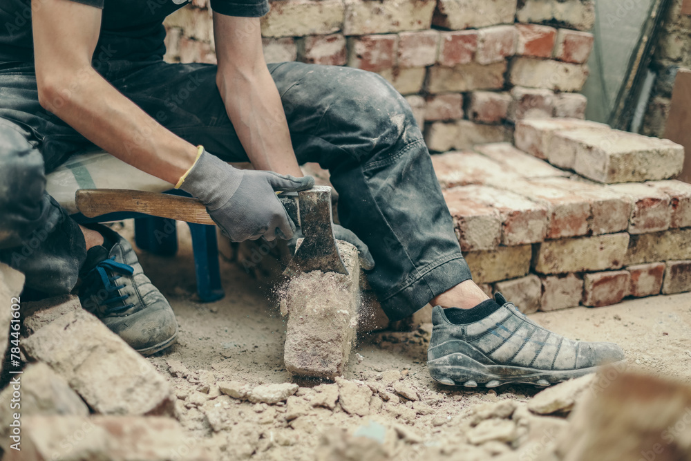 A young guy is cleaning bricks with an axe. A young guy is cleaning bricks with an axe.