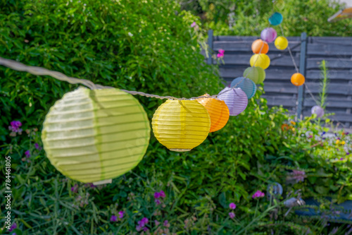 Summerly garden scene with colorful lampions hanging in a row.
