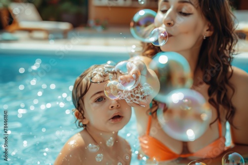 A woman and child having fun blowing bubbles in a pool. Perfect for summer and family leisure concepts