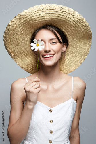 village girl in hat with flower. beautiful smiling young woman with chamomile