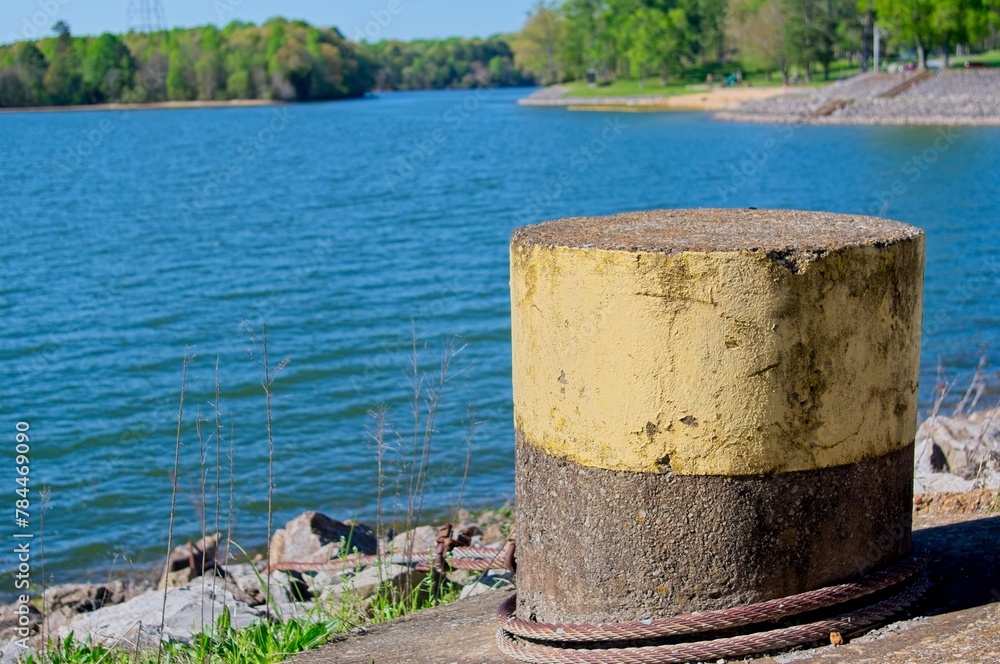 Concrete mooring post with steel cable on lake shore Concrete mooring post with steel cable on lake shore