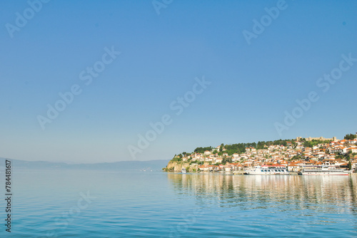 Fototapeta Naklejka Na Ścianę i Meble -  Lake Ohrid, North Macedonia, April 13 2024. Mountain range and peninsula in distance. Ohrid Lake, Macedonia, Europe. The clear mesmerizing waters of lake Ohrid with a beautiful view. 