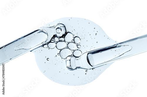 Two pipettes and a drop of cosmetic serum for the skin. Liquid body care product. Macrophotography. Isolated on a white background.