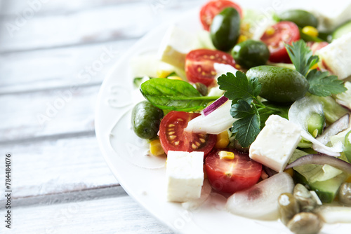 Healthy Salad with Feta Cheese, Green Olives, Baby Spinach, Cucumber, Cherry Tomatoes and Capers. Bright background. Close up.
