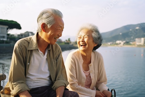 Asian uncle and aunt as they share tender moments walking together on the beach, their love shining bright like the sun setting on the horizon.