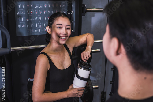 A young Asian woman converses with a man at the gym, striking a friendly chord with smiles and a casual vibe, suggesting a budding romantic interest.