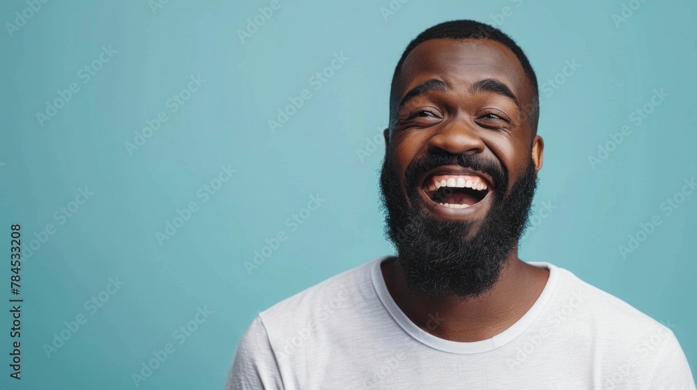 Portrait of a cheerful African American man with a beard wearing a white tshirt against a vibrant blue background Portrait of a cheerful African American man with a beard wearing a white tshirt against a vibrant blue background