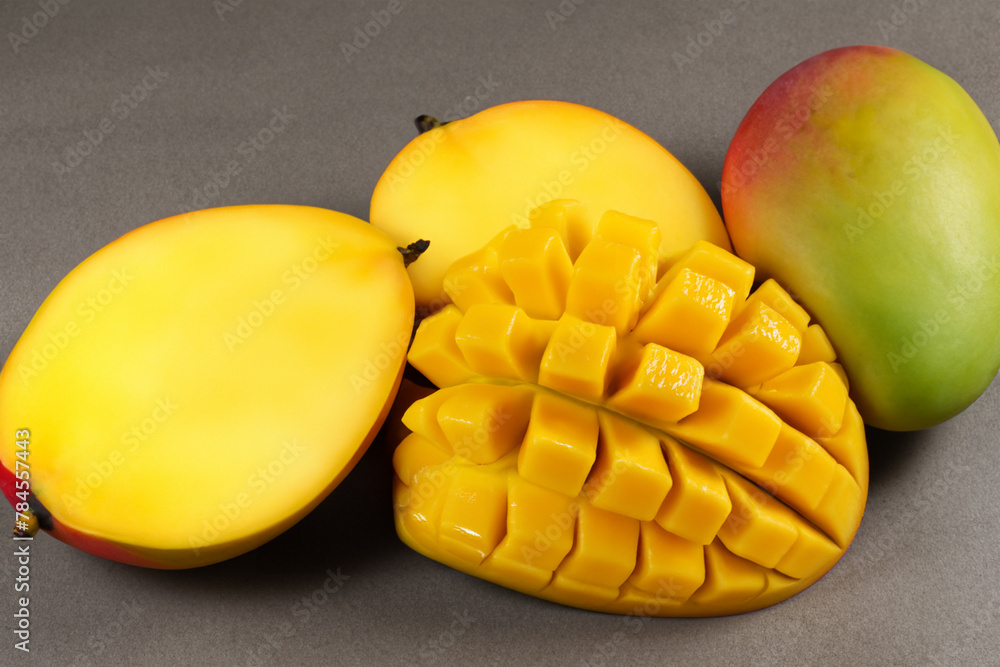 ripe mango. yellow ripe mango halves lie on a gray table, top view, fruit concept