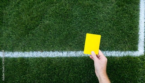Soccer Concept. Yellow foul card in background grass with copy-space.
