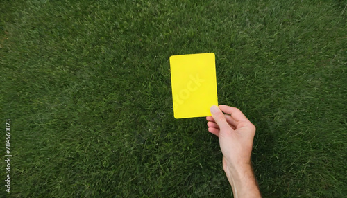 Soccer Concept. Yellow foul card in background grass with copy-space.