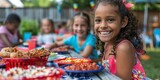 Diverse group of smiling children at outdoor picnic with colorful food plates.