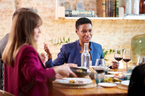 successful business people wearing formal clothes sitting at table with snacks and alcohol and negotiating, discussing plans. Company executives having lunch in restaurant photo