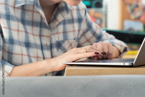 Close-up shot of a woman's hand working on a laptop keyboard. Concept of distance work, online learning and internet surfing