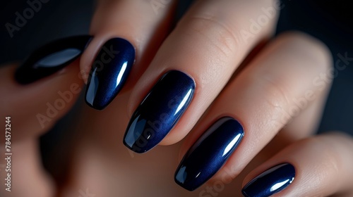 Glamour woman hand with navy blue nail polish on her fingernails. Navy nail manicure with gel polish at luxury beauty salon. Nail art and design. Female hand model. French manicure
