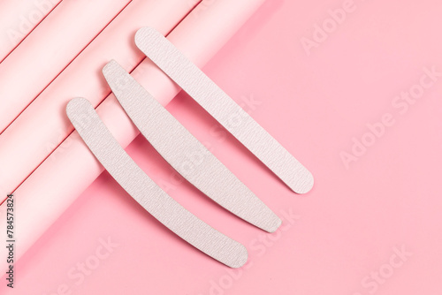 Set of gray nail files of different shapes and different stiffness. Tools for manicure on pastel pink background. Isometric, modern photo. photo