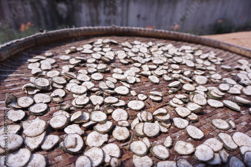 Close-up of raw banana thin slices, a round baked, dried or sun-dried crisp pieces isolated on brown threshing basket in the countryside. Herbal concept for health.
