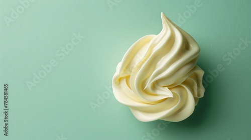 A drop of thick cream resting on a matte mint green  background. photo