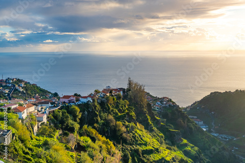 Taditional Madeiran houses in Funchal behind a banana plantation and ocean sunset. photo