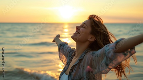 Happy woman standing with open arms on the beach at sunset. success concept,