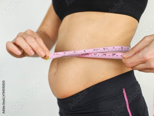 Fat woman hand holding measurement tape on her belly fat