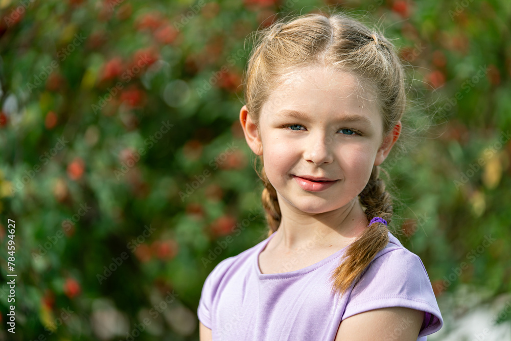 Obraz premium lächelndes, blondes Mädchen mit Zöpfen in lila Kleidung schaut an einem sonnigen Tag in die Kamera