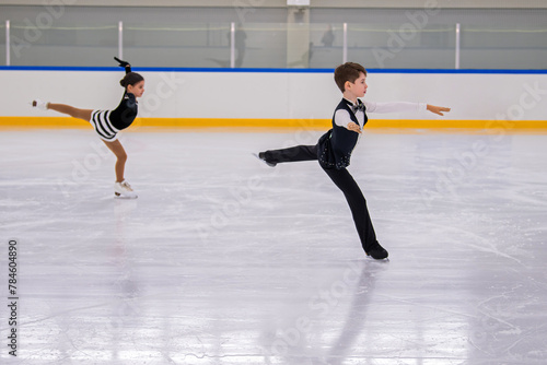 A boy and girl ice skaters are performing a routine on the ice.