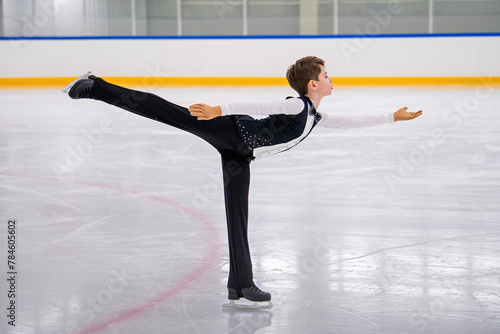 A young boy is skating on ice with his arms outstretched. photo