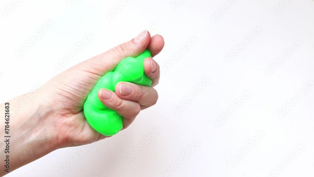 The girl kneads green slime. Woman's hands stretch bright green slime close-up on a white background. Anti-stress toy for relaxation. A fun sensory activity. Toy store concept The girl kneads green slime. Woman's hands stretch bright green slime close-up on a white background. Anti-stress toy for relaxation. A fun sensory activity. Toy store concept