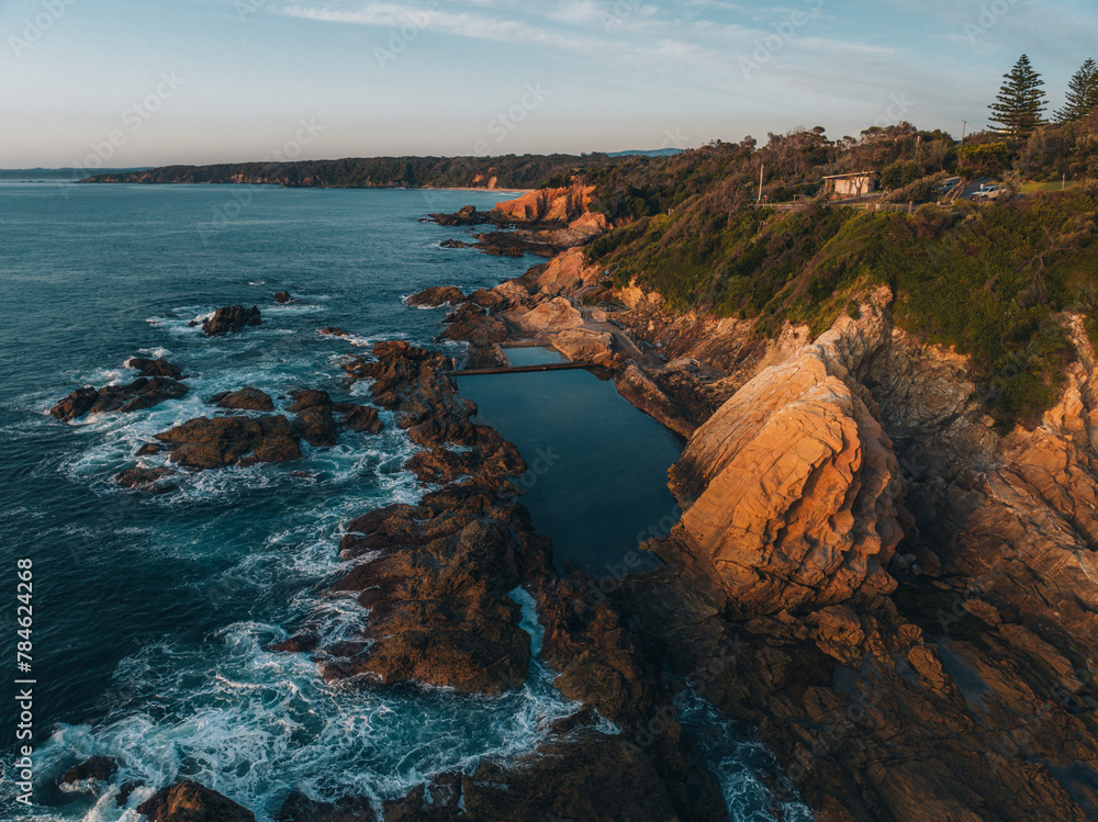 Aerial drone view of Blue Pool in Bermagui during sunrise sunset with blue sky and reflection. New South Wales, Australia