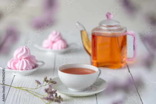 Glass teacup and teapot on white wooden table
