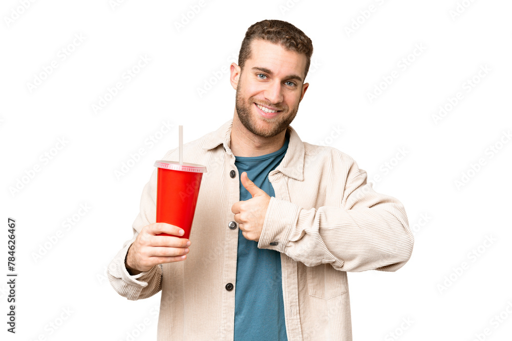 Young handsome blonde man holding soda over isolated chroma key background giving a thumbs up gesture
