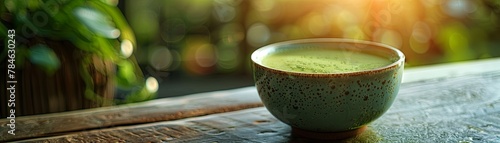 A cup of matcha green tea on a wooden table with a blurred background of leaves and sunlight.