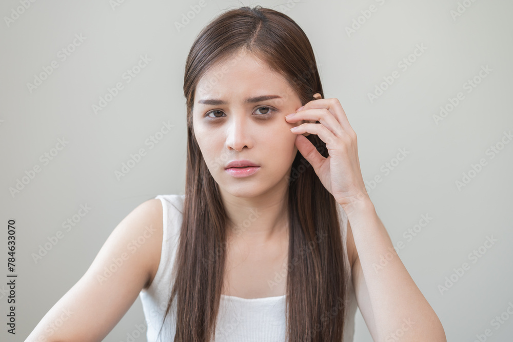 Bored, insomnia asian young woman, girl looking at camera, hand touching under eyes with problem of black circles or panda puffy, swollen and wrinkle on face. Sleepless, sleepy healthcare person. Bored, insomnia asian young woman, girl looking at camera, hand touching under eyes with problem of black circles or panda puffy, swollen and wrinkle on face. Sleepless, sleepy healthcare person.
