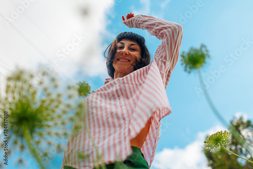 Photo of a girl dancing in a flower field against the sky.
