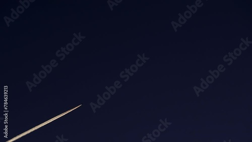 Airplane at cruising altitude with contrail against sky. Chemtrail or condensation trails.